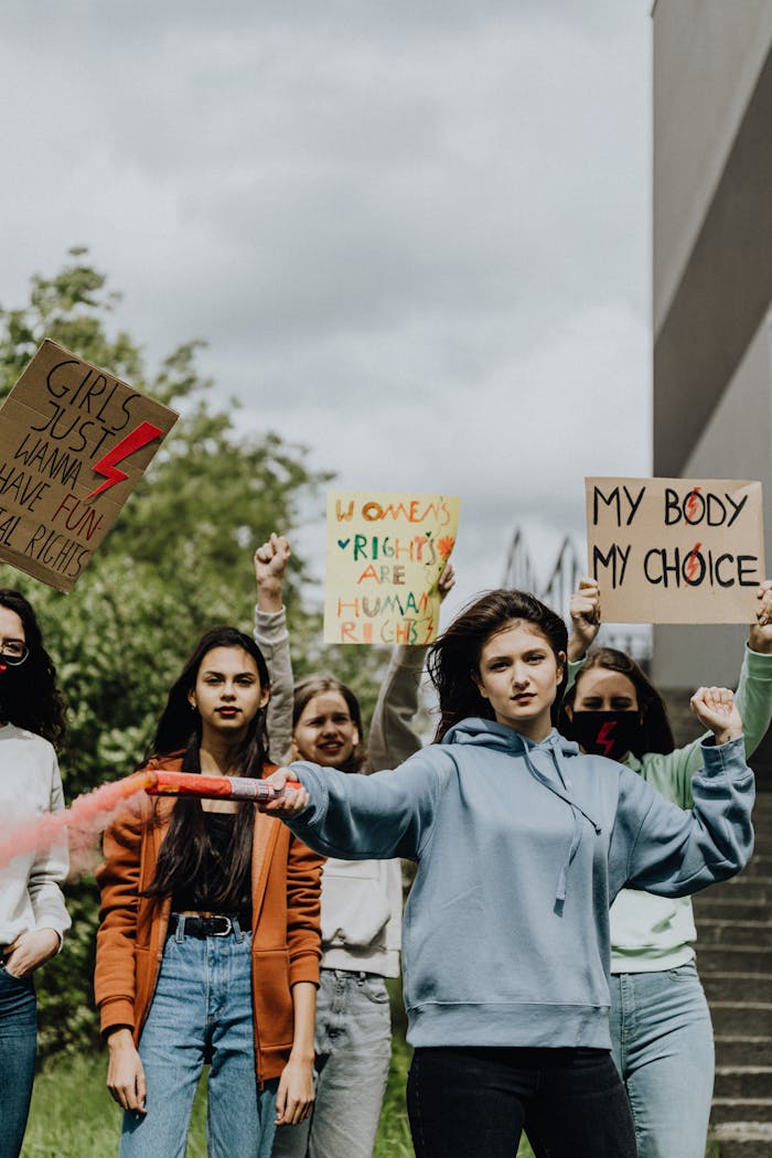 A diverse group of young women holding protest signs advocating for women's rights and empowerment.